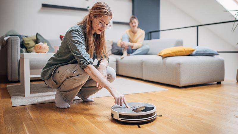 Mulher a ligar o aspirador robot na sua sala